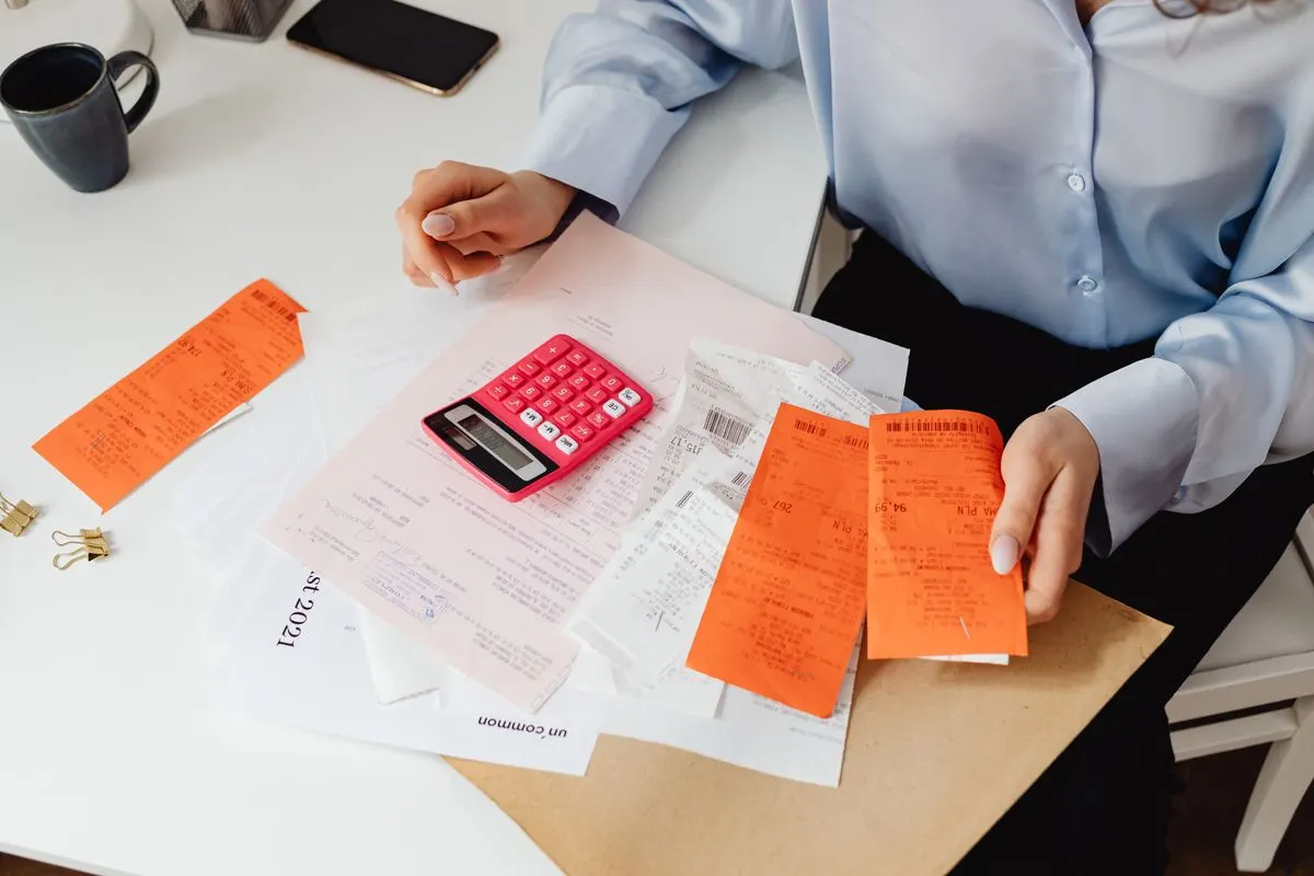 A person holding receipts and using a calculator to work out deductible business expenses