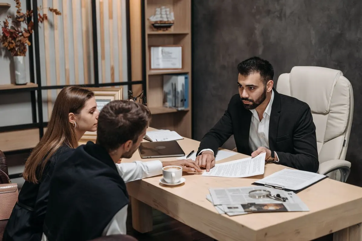 An advisor discussing legal and financial documents with a client at an office desk