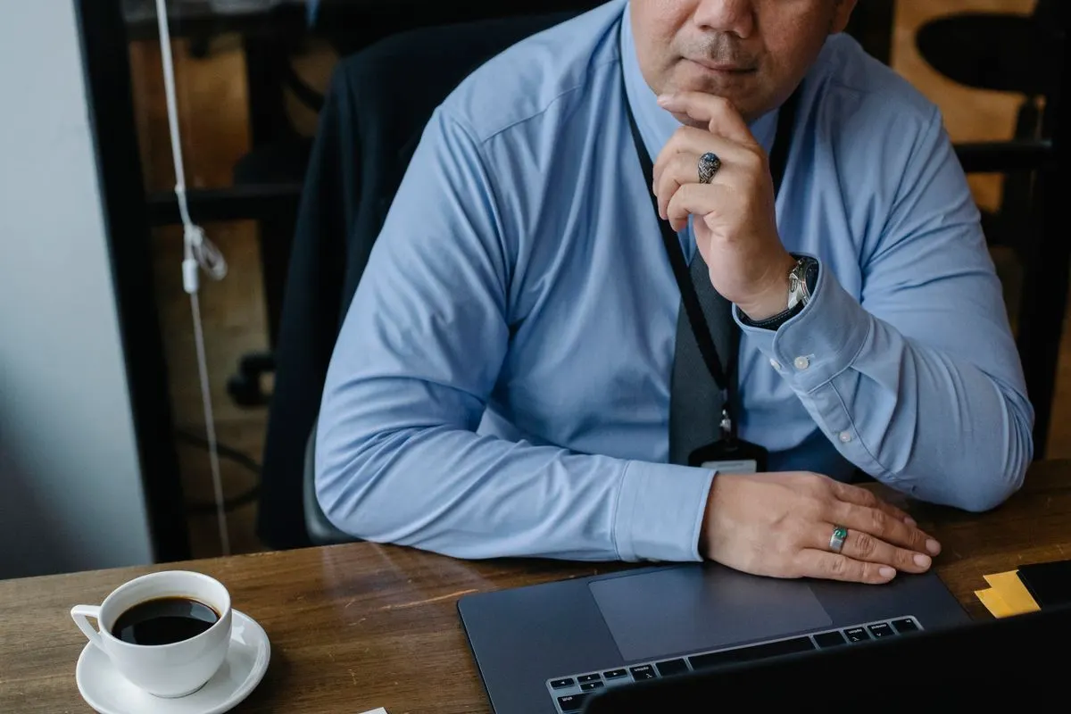A serious businessman touching his chin while working on a laptop