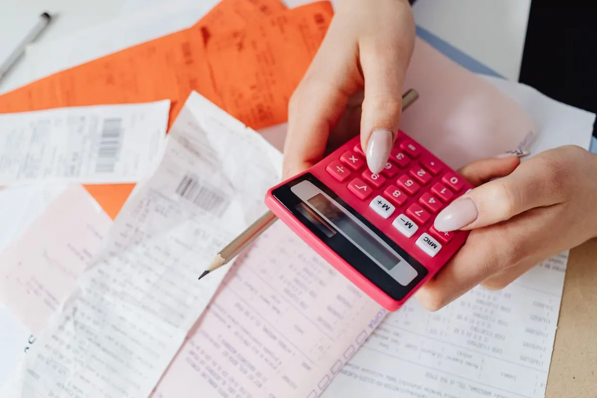 A close-up shot of a person using a calculator to work out GST for a Singapore accounting services invoice