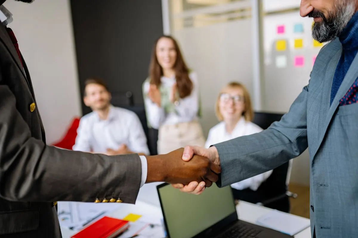 Two colleagues shaking hands in a professional office setting, representing a corporate secretarial services handover